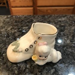 Vintage Bone China Boot With a Baby with Gold Trim. The Baby is holding a flower. Size 3 1/2 inches wide and 1 1/2 inches tall.  Preowned 