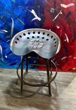 Industrial-Style Home Decor Accent Piece Artwork! Metal Tractor seat bar stool featuring an adjustable swivel height mechanism & a perforated seat des