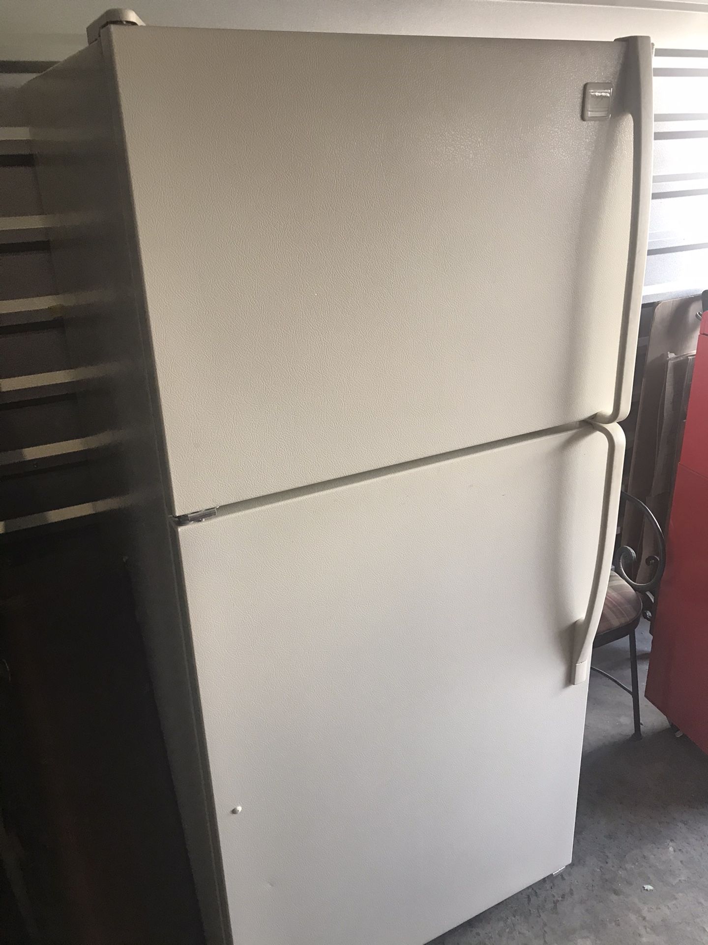 Clean, white top freezer over refrigerator. With ice maker.