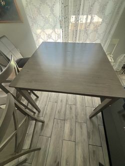 A high wood table and 3 grey  color chair