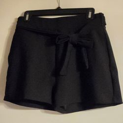 A pair of black shorts with two side pockets and belt