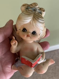 Vintage porcelain girl reading a book and an angel blowing kiss