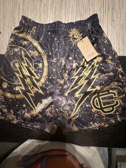 Corrupted Creative shorts with gold lightning bolts, celestial symbols and a circular emblem on a dark background
