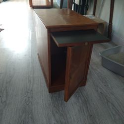 Small Wooden Cabinet That Opens Up And Has A Drawer And Magazine Holder On The Back