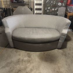 Gray sleeper loveseat with pull-out mattress and matching ottoman.
