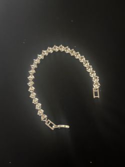 Elegant Heart Tennis Bracelet has a series of linked, faceted settings. This piece is crafted with a metallic finish and features a secure fold-over c