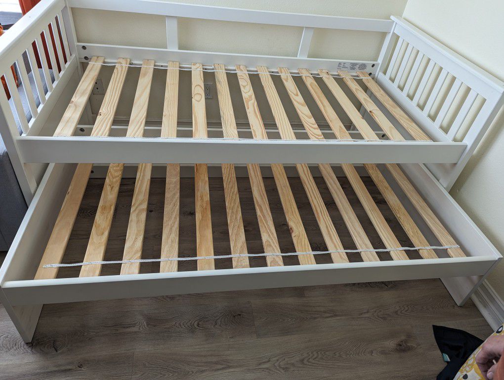 White wooden twin bed frame with twin trundle