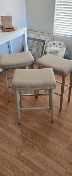 Set of 3 upholstered backless saddle bar stools.
