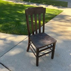 Vintage wooden chair with classic schoolhouse slat-back design with weathered dark brown finish