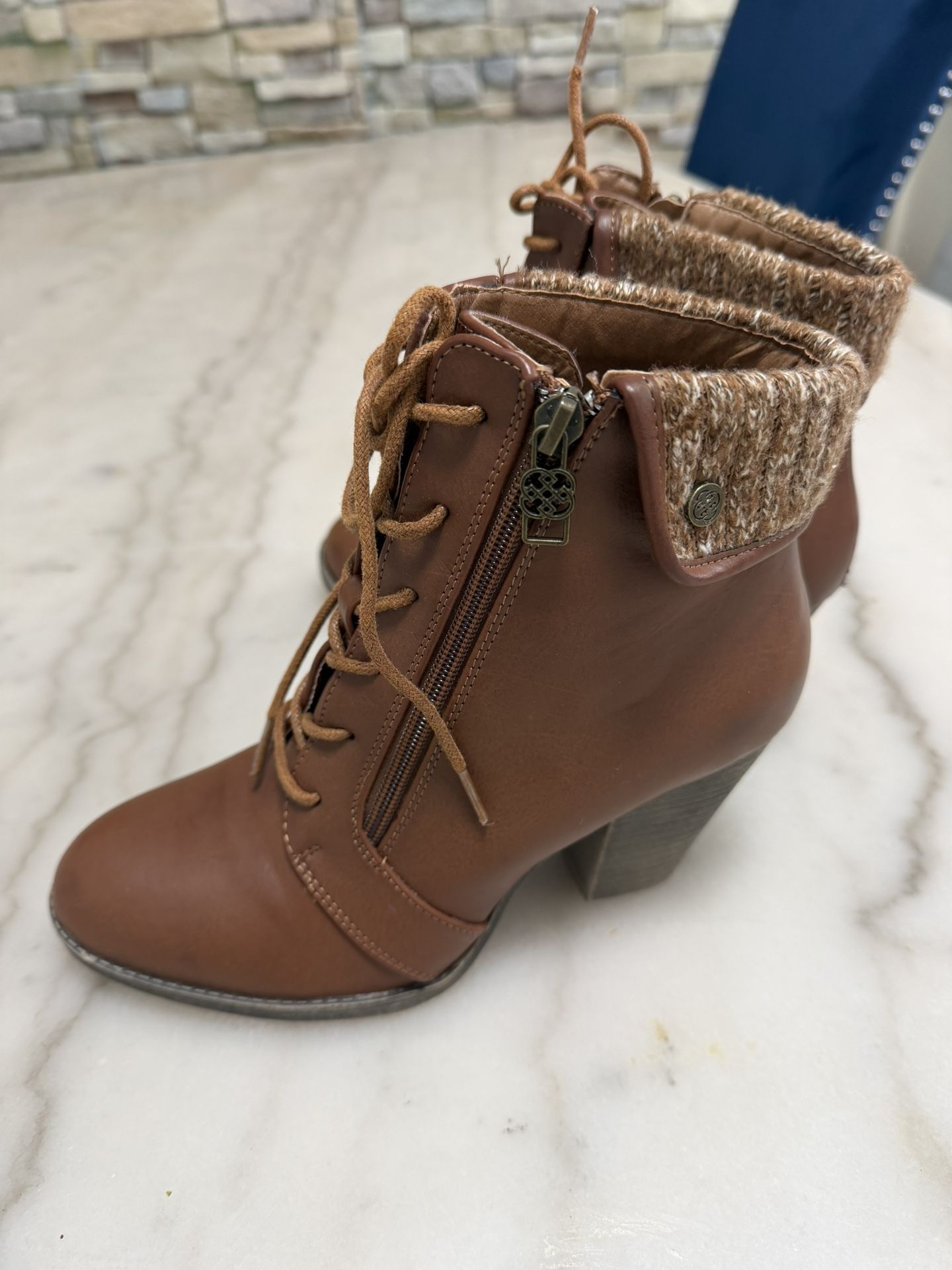 This is a pair of Daisy Fuentes Stormi brown faux leather combat ankle boots with a knit cuff and chunky block heel. Size.7