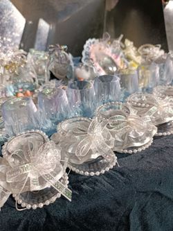 Baby shower favors / party favors featuring miniature bassinet baskets with baby figurines, decorative clear plastic goblets filled with shredded meta