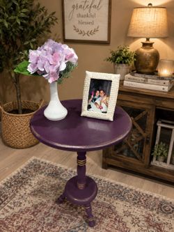 Round pedestal accent table in a eggplant color