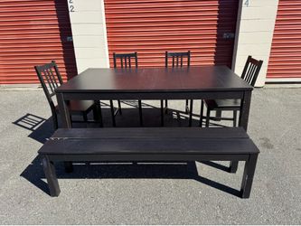 Black Ikea wooden table and four chairs and a bench
