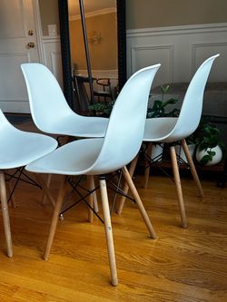 Modern white plastic shell dining chairs with wooden legs and black metal cross struts