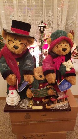TEDDY BEAR TRIO WITH SILENT NIGHT MUSIC SHEETS ON WOODEN FRAME WITH LAMP POST BEHIND THEM.