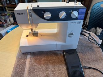 Reliable Pfaff hobby 1042 sewing machine is white with a dark grey control panel. This German-designed model has multiple stitch patterns, a foot peda