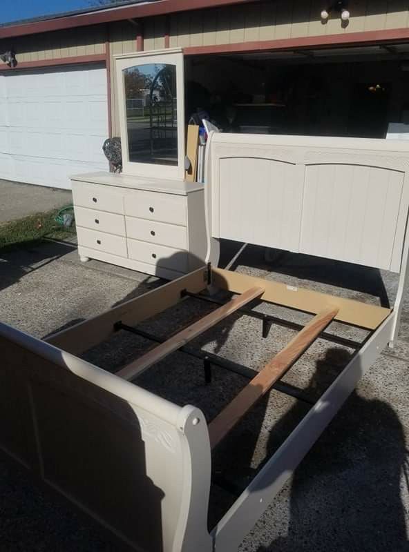 Cream colored dresser with mirror and full size bed frame.