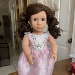 The doll in the image is an Our Generation 18" Amina Doll with a Ballroom Dress. This doll has brown eyes that open and close, and long, wavy brown ha