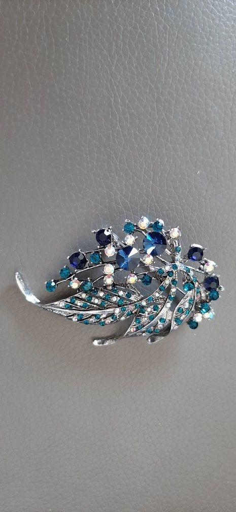 Silver tone brooch with green and blue stones.