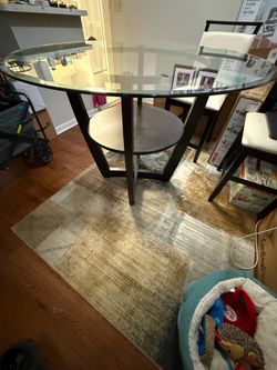 48-inch round glass-top dining table with a dark wood base and lower shelf.