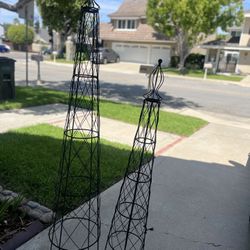 Two black metal garden obelisk trellises.