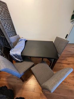 Black dining table with four gray chairs