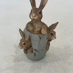 Vintage resin figurine of three bunnies emerging from a cracked egg.