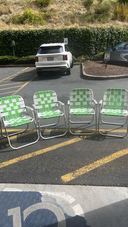 That is a classic green-and-white webbed aluminum folding lawn chair featuring a lightweight metal frame and woven straps