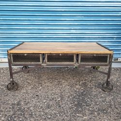 Rustic industrial style coffee table on wheels. Metal body with wood top. 3 metal basket 