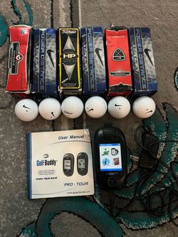 This image shows a Golf Buddy Tour handheld GPS rangefinder displaying with six Nike Golf ball