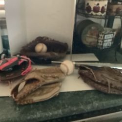 Family baseball package including four gloves, bat and 2 balls. There is a first baseman’s glove, adult fielders glove and. Couple of kid’s All one pr