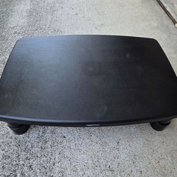 Versatile AmazonBasics black footrest. Works great as a monitor stand too. Measures about 15 inches long and 11 inches wide. Super handy for home offi