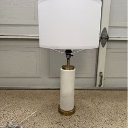 This Brightech Arden LED table lamp features a white marble cylinder base and brass-finished accents.