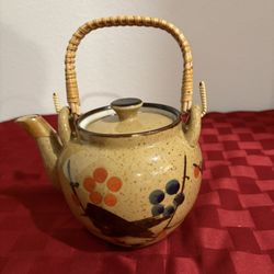 vintage Otagiri stoneware teapot with a wicker/rattan handle and a floral design.