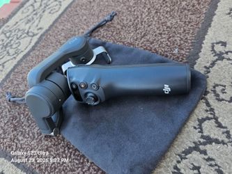 DJI Osmo Mobile 6 3-axis smartphone gimbal stabilizer in gray, resting on its storage pouch.