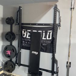 RX Profile ONE Folding Squat Rack with rstorage accessories, barbell and rubber grip plates.