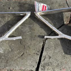 two metal shelf brackets designed in a tree branch style, with a small bag of mounting hardware 