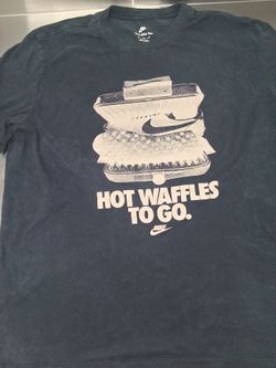 black Nike Sportswear t-shirt features a graphic print of a shoe inside a waffle iron with the text "HOT WAFFLES TO GO."