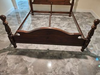 King sized wood bed frame with rails.