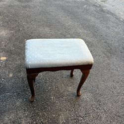 Vintage stool. Wooden, with curved legs. Seat upholstered in light blue fabric with a subtle geometric pattern.