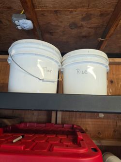 Buckets of rice, sugar, flour, and a  big bag of flour.