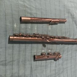  silver-plated student concert flute laid out on a textured blue surface, displaying its three