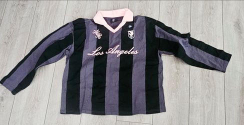 ANGEL CITY FC Striped Long Sleeve Soccer Jersey from Pacsun, featuring a contrasting pink collar and "Los Angeles" script across the chest.
