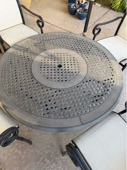 Cast aluminum patio dining set in a black finish featuring a round lattice-top table and chairs with scroll arms.