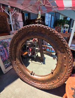 The round mirror features a thick, rustic-style frame.