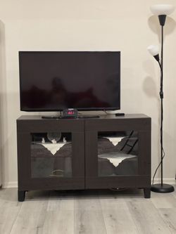 "Complete entertainment/living room set including Samsung flat-screen TV, dark wood media console with glass doors, IKEA floor lamp, and digital elect