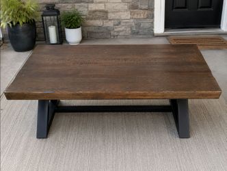 Rustic coffee table with solid wood top and black metal base.