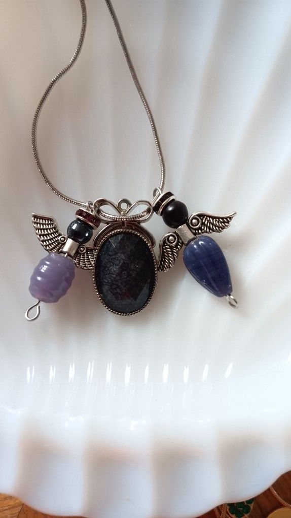 Two Angels Next To A Pendant On A Silver Chain