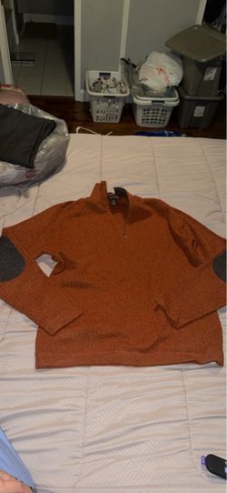 orange or rust-colored quarter-zip pullover sweater laid flat on a bed, featuring a mock neck and contrasting elbow patches. Size L