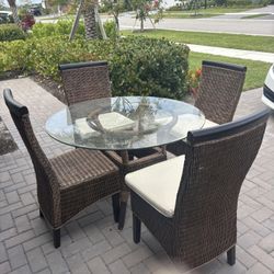 Round Glass Table With Four Wicker Chairs and Cushions